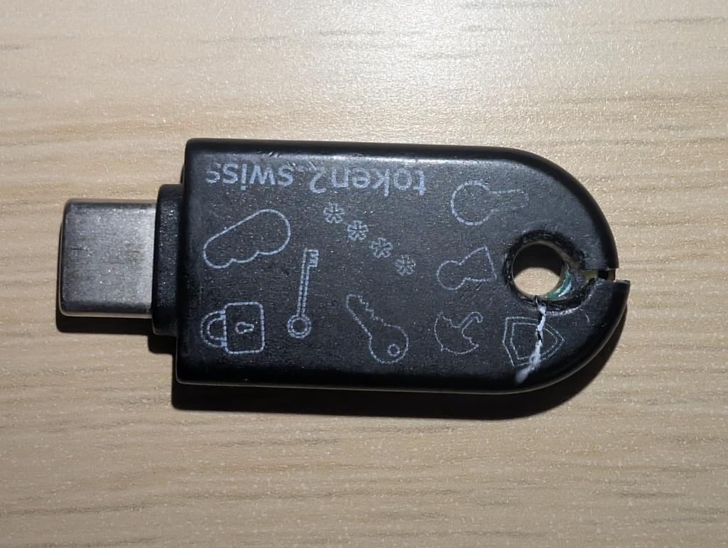 A small USB-C security key. There is are two cracks originating from the hole at the end, used for attaching it to a keyring, causing the plastic casing to fall apart.